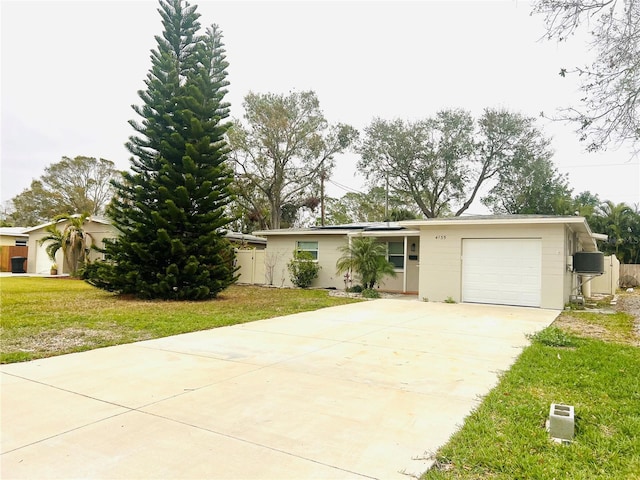 single story home with a garage, a front lawn, and solar panels