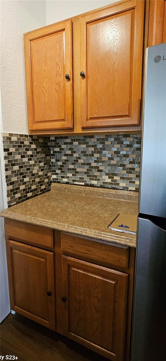 interior details featuring dark hardwood / wood-style floors, stainless steel fridge, and decorative backsplash