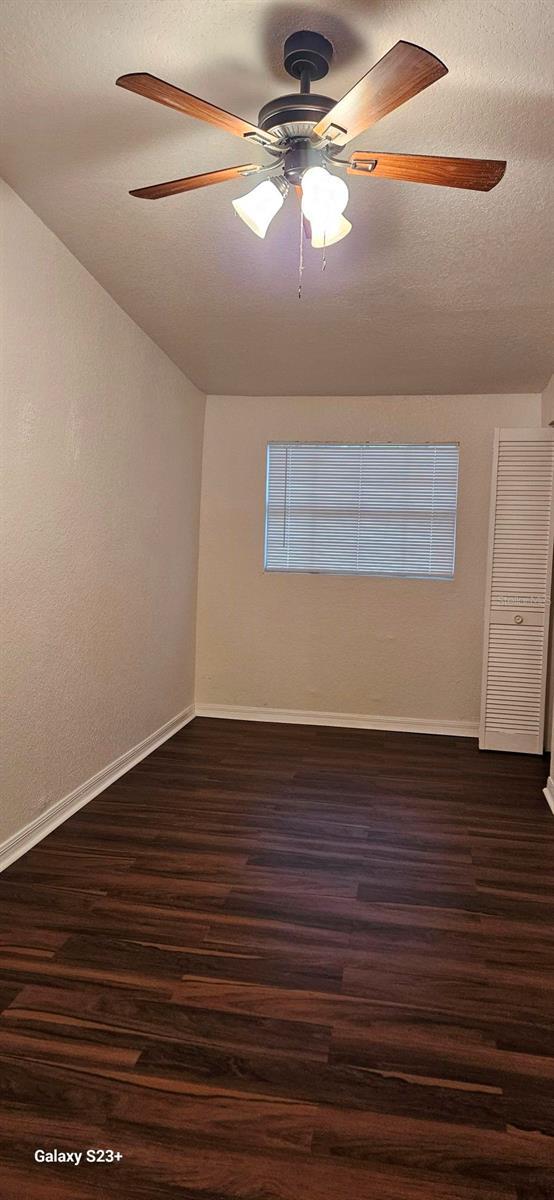 empty room with ceiling fan, dark hardwood / wood-style floors, and a textured ceiling