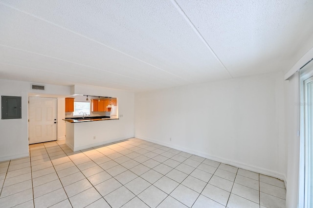 unfurnished living room with electric panel, a textured ceiling, and light tile patterned floors