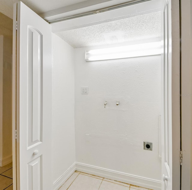 laundry room with electric dryer hookup, light tile patterned floors, and a textured ceiling