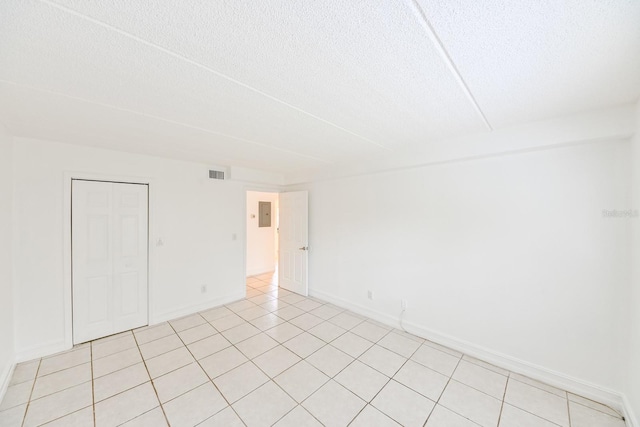 tiled empty room with a textured ceiling