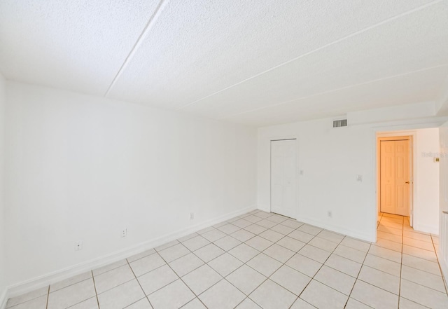 tiled empty room with a textured ceiling