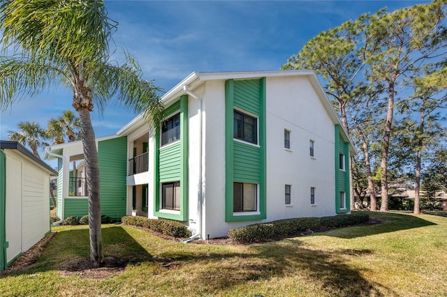 view of side of property featuring a yard and a balcony