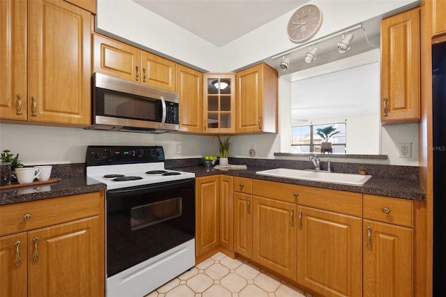 kitchen with range with electric cooktop, sink, and dark stone countertops