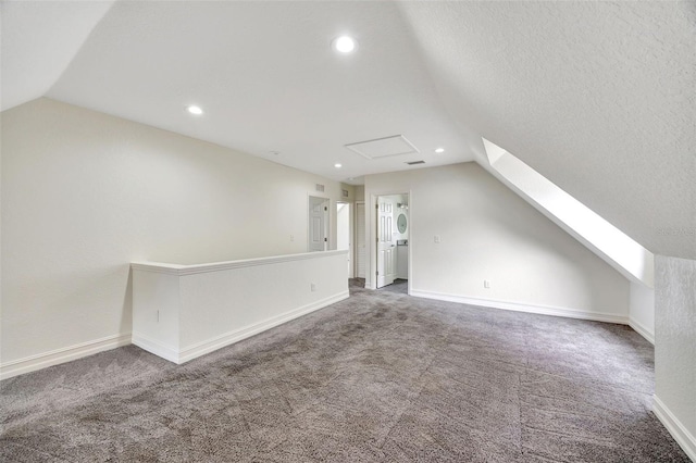 additional living space with vaulted ceiling, a textured ceiling, and carpet flooring