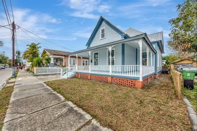 country-style home with covered porch and a front lawn