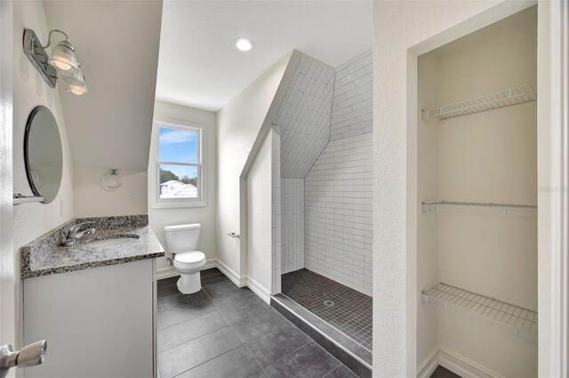 bathroom with tile patterned floors, vanity, toilet, and a tile shower