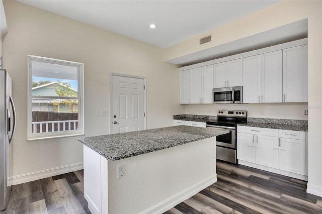 kitchen featuring dark stone countertops, a center island, white cabinets, and appliances with stainless steel finishes