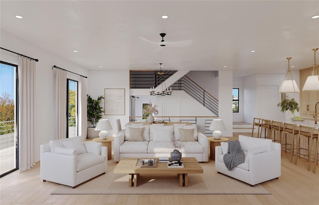 living room with ceiling fan with notable chandelier and light hardwood / wood-style floors