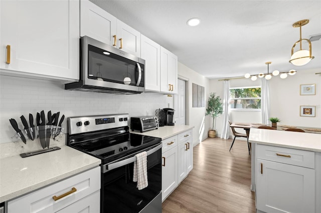 kitchen featuring tasteful backsplash, white cabinetry, appliances with stainless steel finishes, and pendant lighting