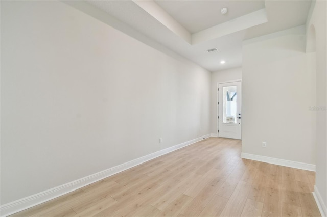 spare room with light hardwood / wood-style flooring and a tray ceiling