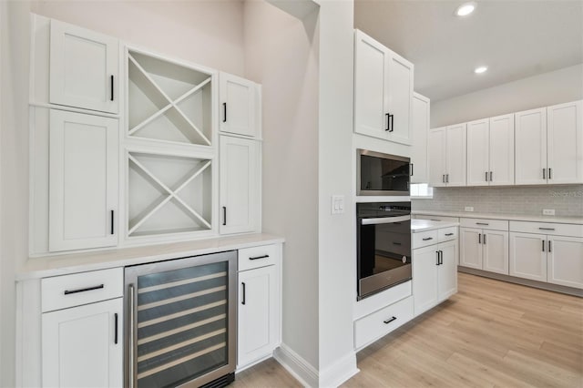 kitchen featuring white cabinets, built in microwave, beverage cooler, and wall oven