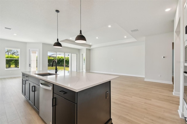 kitchen featuring sink, decorative light fixtures, an island with sink, and light wood-type flooring