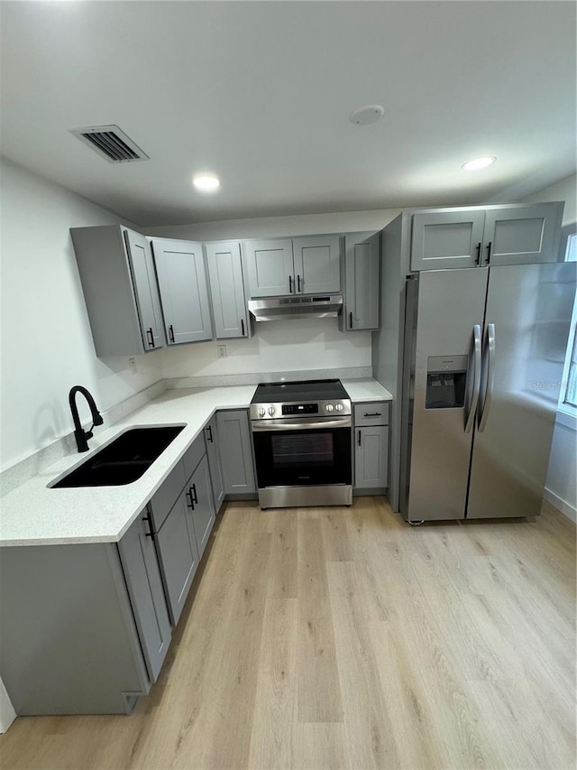 kitchen with stainless steel appliances, sink, gray cabinetry, and light wood-type flooring