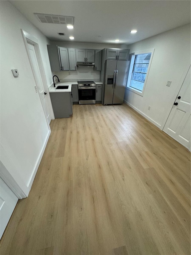 kitchen featuring appliances with stainless steel finishes, sink, gray cabinetry, and light hardwood / wood-style flooring