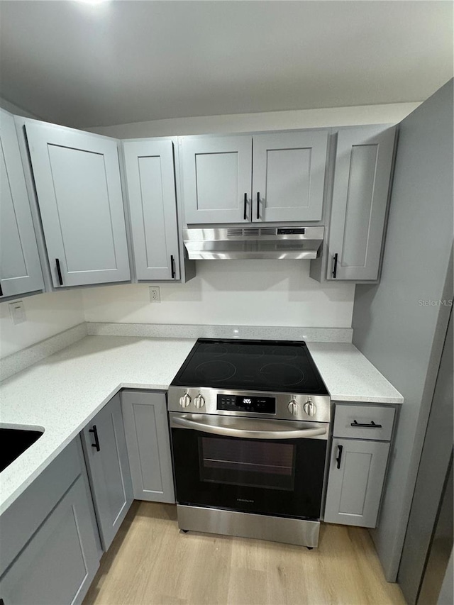 kitchen with light hardwood / wood-style floors, stainless steel range with electric cooktop, and gray cabinetry