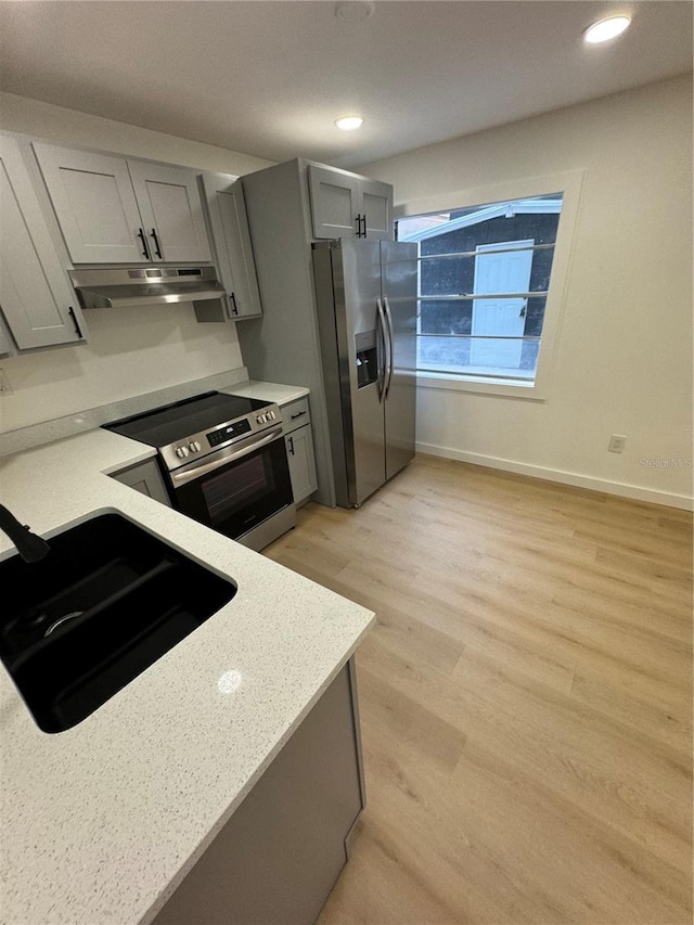 kitchen featuring sink, gray cabinetry, light stone counters, stainless steel appliances, and light hardwood / wood-style floors