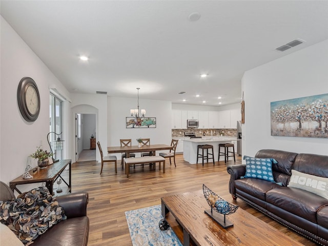 living room featuring light hardwood / wood-style flooring and an inviting chandelier