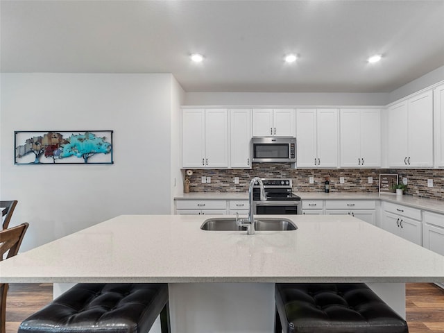 kitchen with sink, a kitchen island with sink, a breakfast bar, and stainless steel appliances