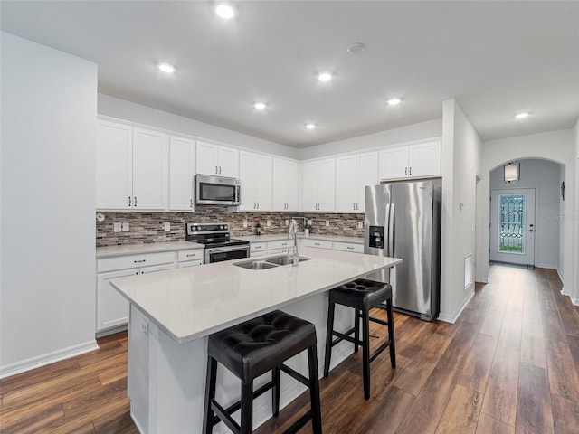 kitchen featuring a kitchen breakfast bar, white cabinets, appliances with stainless steel finishes, and a kitchen island with sink