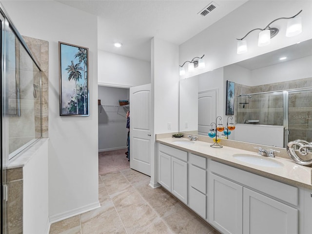 bathroom featuring a shower with shower door and vanity