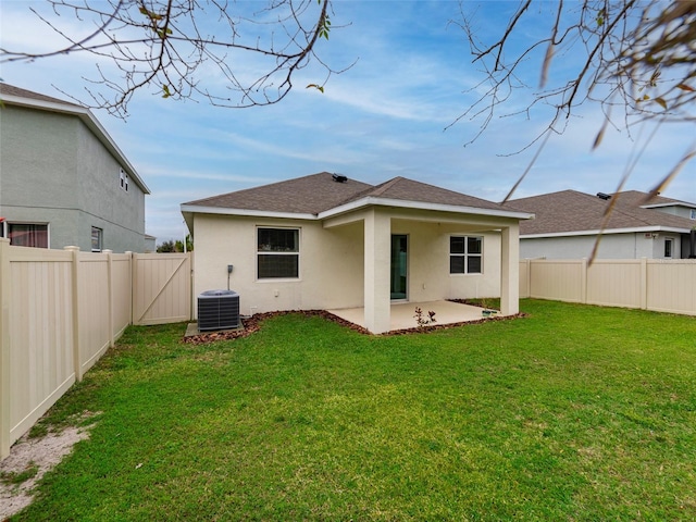 rear view of property with cooling unit, a patio area, and a lawn