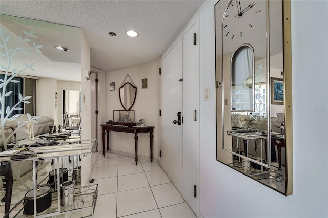 hall with light tile patterned floors, a textured ceiling, and recessed lighting