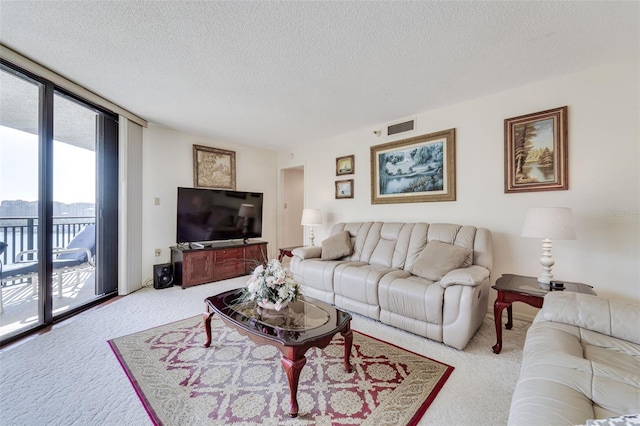 carpeted living room featuring a textured ceiling, a wall of windows, and visible vents