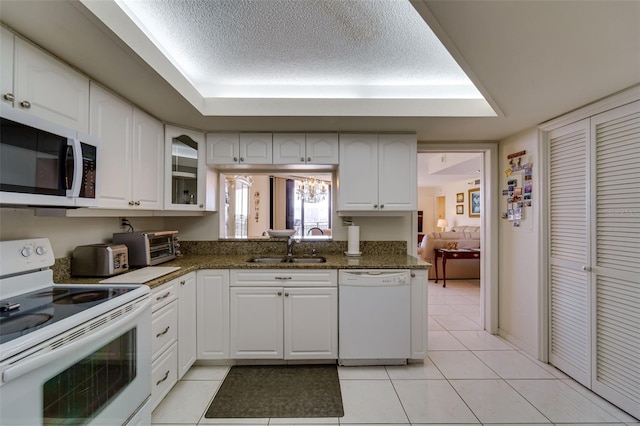 kitchen featuring white appliances, a sink, a textured ceiling, and light tile patterned floors