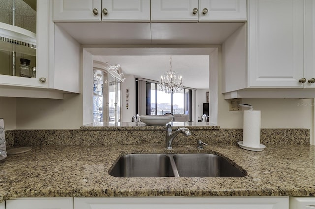 kitchen featuring light stone counters, a sink, glass insert cabinets, and white cabinets