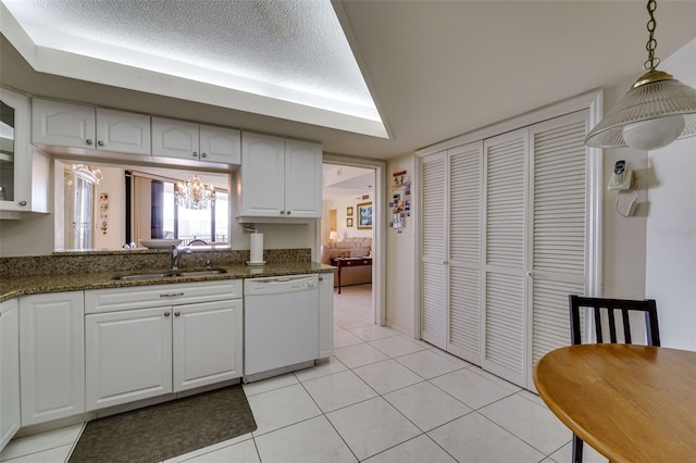 kitchen featuring light tile patterned floors, white dishwasher, a sink, white cabinets, and decorative light fixtures