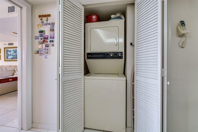 clothes washing area with laundry area, light tile patterned floors, visible vents, and stacked washer and clothes dryer