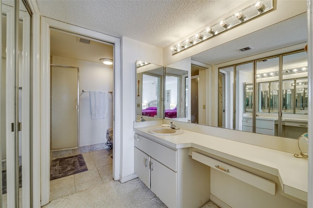 full bath with a stall shower, visible vents, a textured ceiling, and vanity