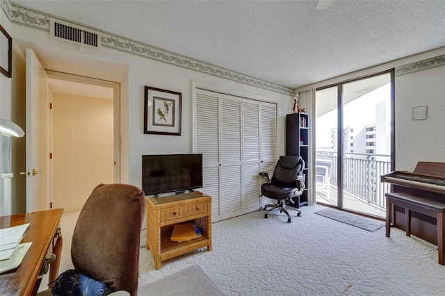 carpeted office space featuring expansive windows, visible vents, and a textured ceiling