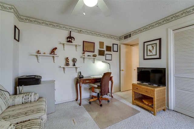 home office with a textured ceiling, carpet flooring, visible vents, and a ceiling fan