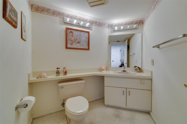 half bathroom with vanity, toilet, and baseboards