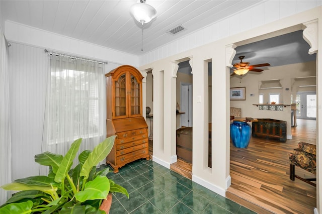 interior space with dark tile patterned floors, ceiling fan, and ornate columns