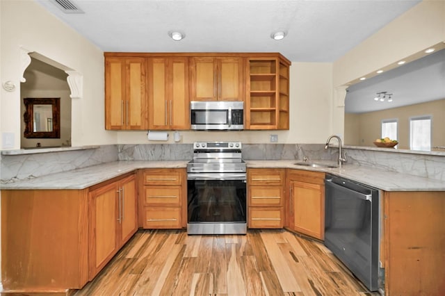 kitchen with appliances with stainless steel finishes, sink, light wood-type flooring, and kitchen peninsula