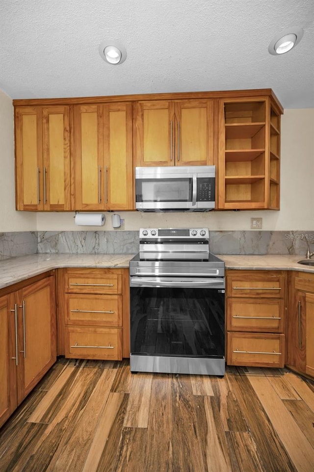 kitchen with appliances with stainless steel finishes, dark hardwood / wood-style floors, sink, and a textured ceiling