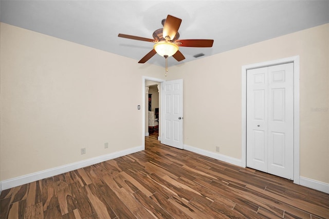 unfurnished bedroom with dark wood-type flooring, a closet, and ceiling fan