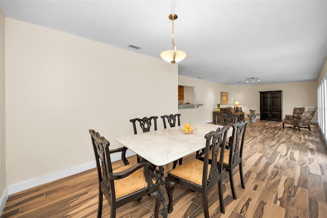 dining area featuring rail lighting and hardwood / wood-style floors