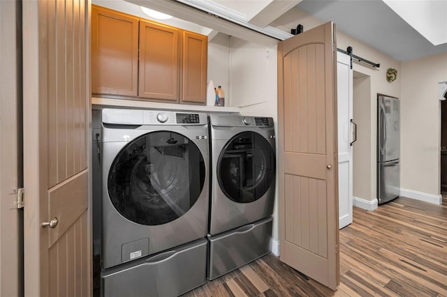 546 Orangewood Dr, Dunedin, FL 34698 - washroom with independent washer and dryer, cabinet space, a barn door, wood finished floors, and baseboards