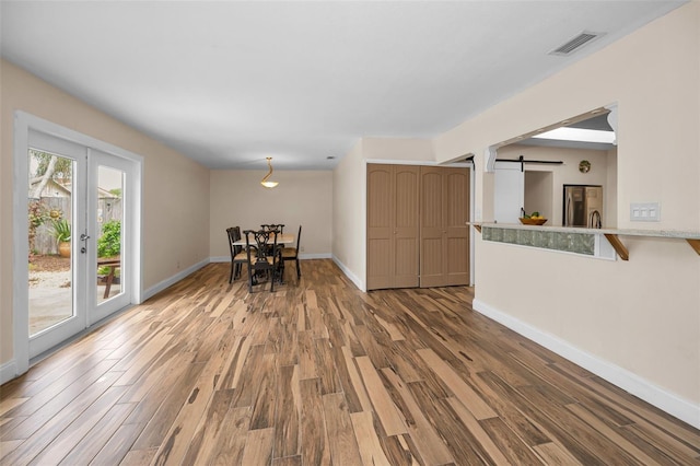 546 Orangewood Dr, Dunedin, FL 34698 - dining area featuring a barn door, wood finished floors, and baseboards