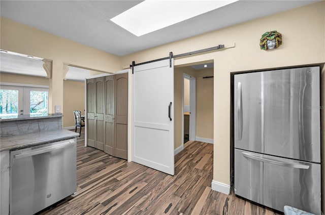 546 Orangewood Dr, Dunedin, FL 34698 - kitchen featuring appliances with stainless steel finishes, dark wood finished floors, a barn door, baseboards, and french doors