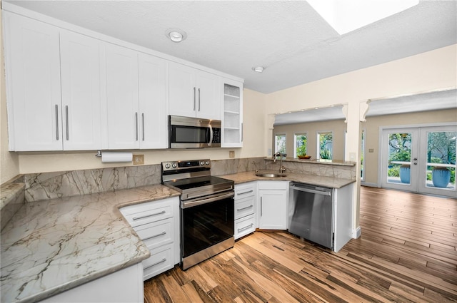 546 Orangewood Dr, Dunedin, FL 34698 - kitchen featuring appliances with stainless steel finishes, a sink, wood finished floors, white cabinetry, and french doors