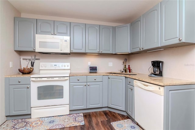 kitchen with gray cabinets, sink, dark wood-type flooring, and white appliances