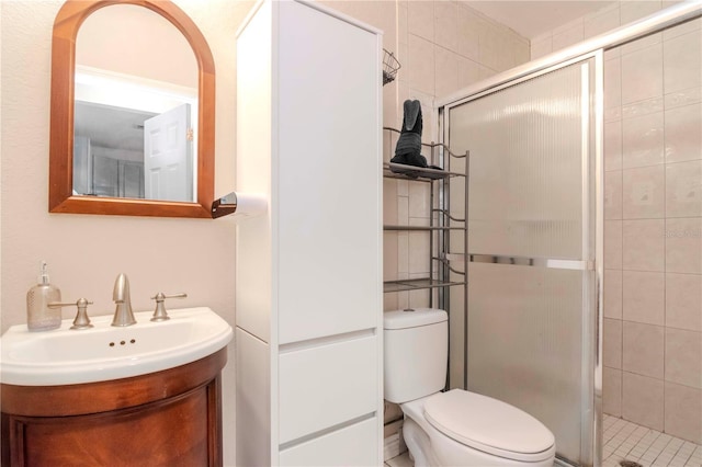 bathroom featuring vanity, toilet, and a shower with shower door