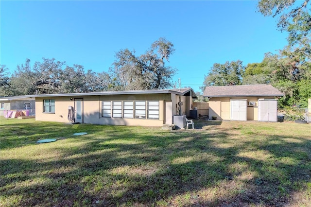 back of property with a yard and a storage unit