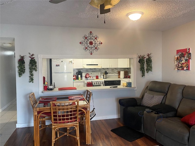 living room with dark wood-type flooring, ceiling fan, and a textured ceiling